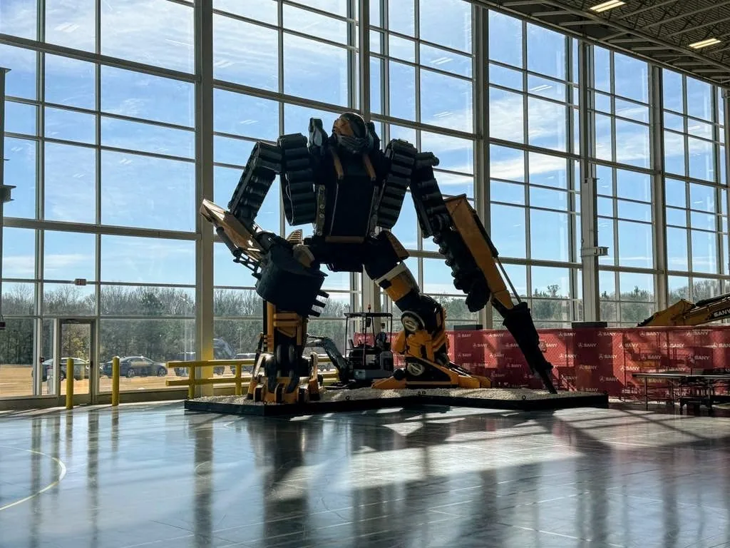 A large walking machine with articulated legs standing in a glass-walled hall