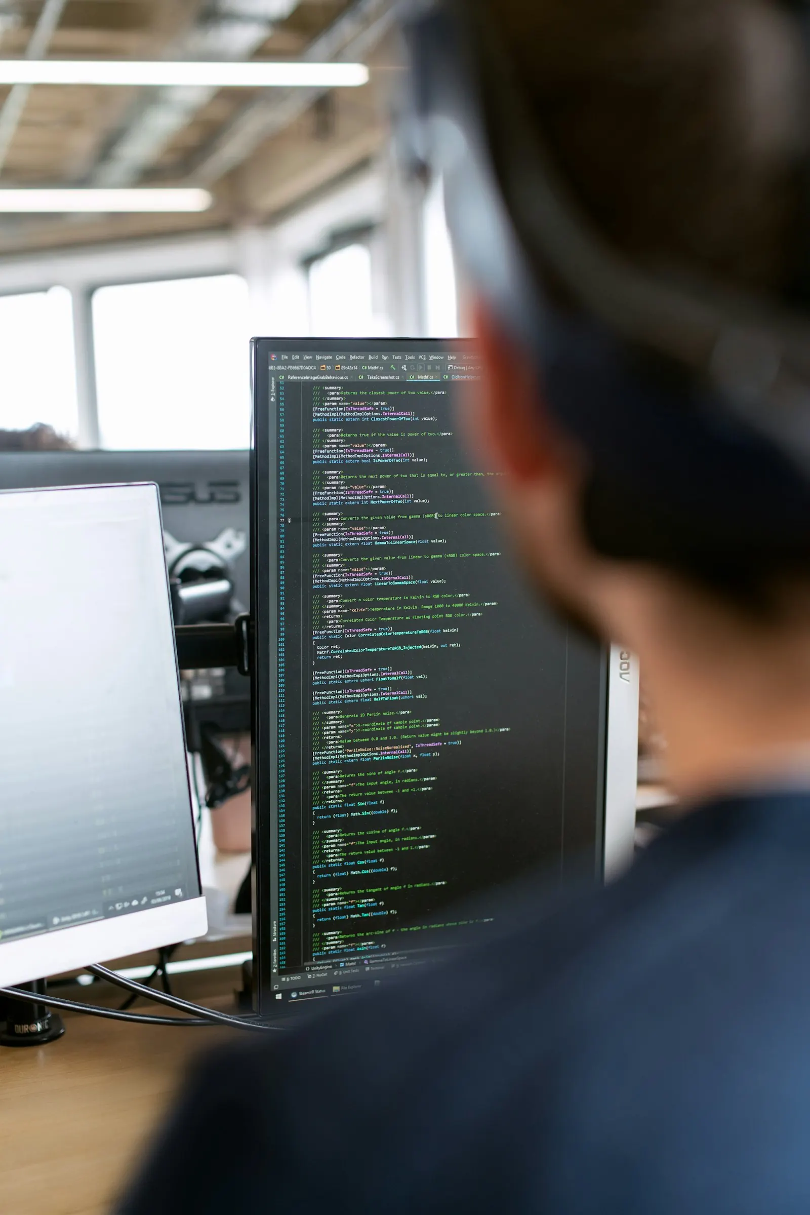An engineer reading code on a monitor in a dim room