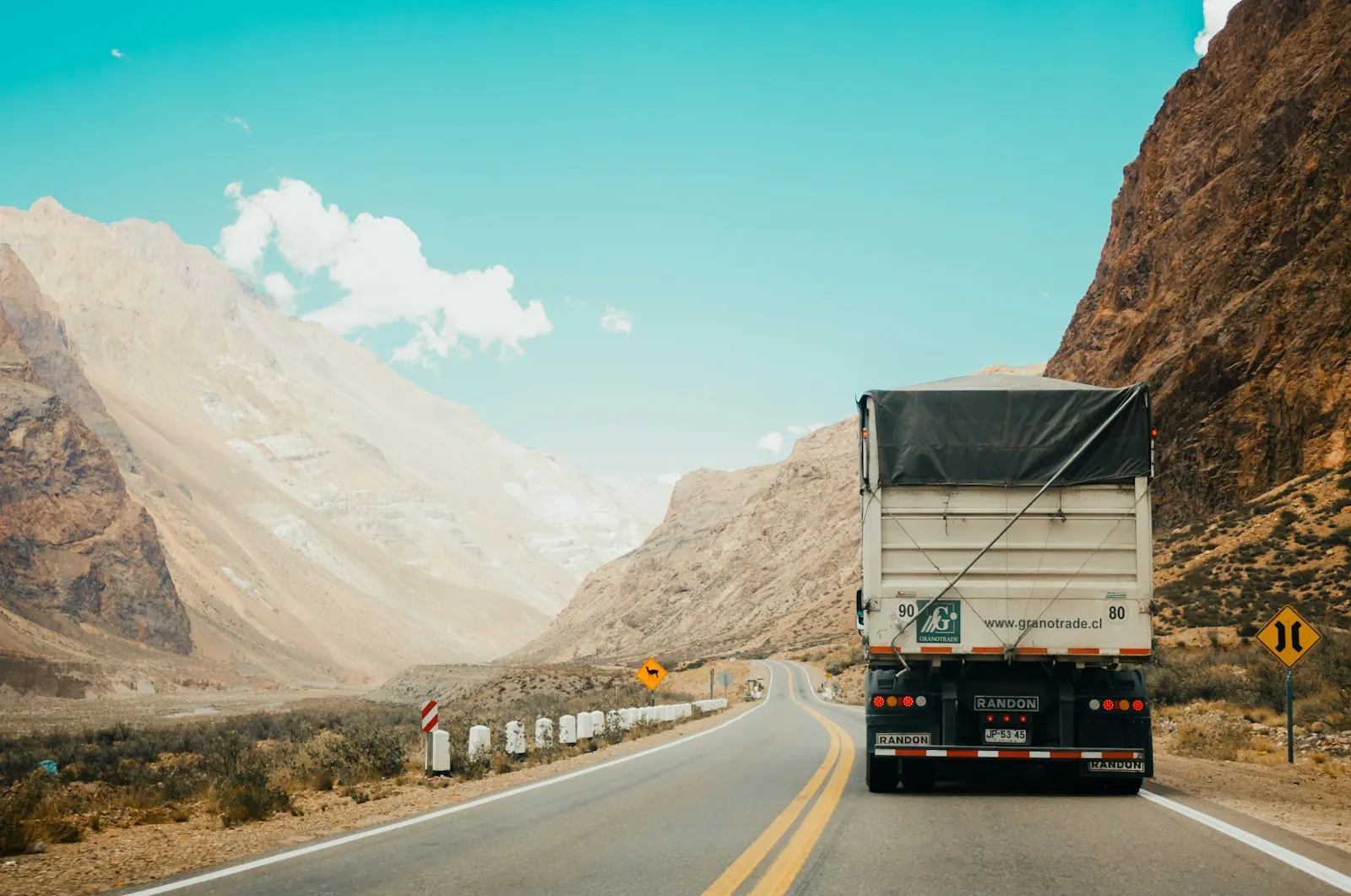 A freight truck on an open road between hills
