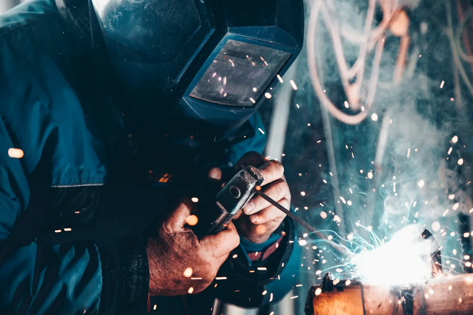 A welder striking an arc, sparks scattering across the frame